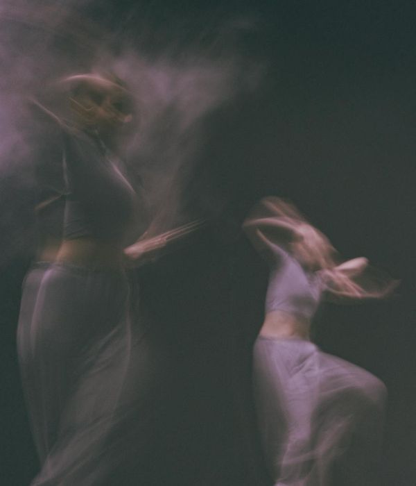 Woman performing a fluid cardio movement in a dark studio with cyan light trails.